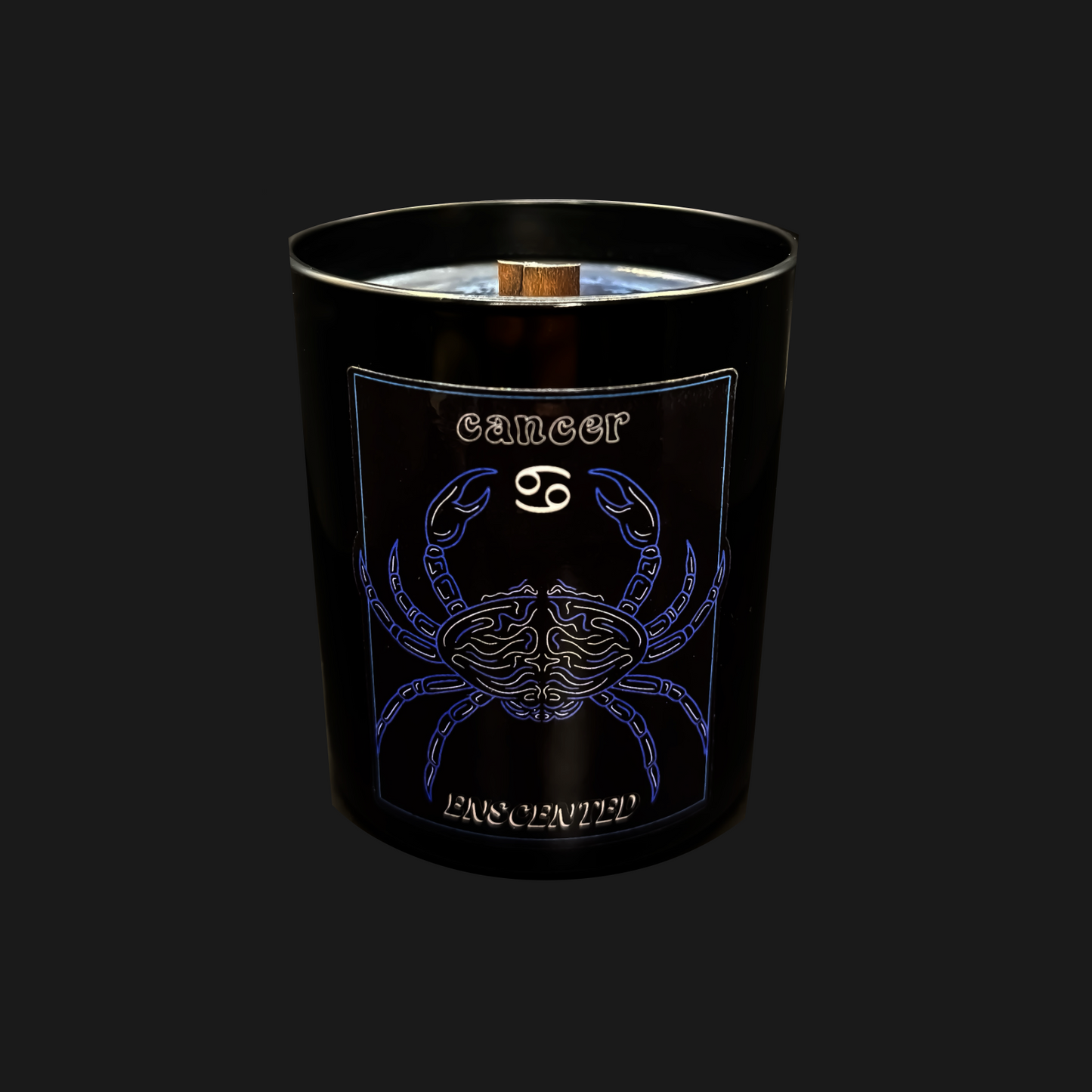 A black candle with a blue and white design featuring the Cancer zodiac sign as a crab, along with the name 'Cancer' written on it. The candle has a wooden wick and emits a slight frosted appearance.