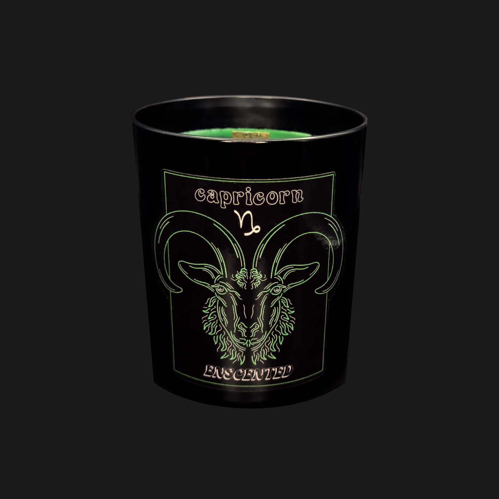 A black soy wax candle with a green tint, featuring the Capricorn zodiac sign illustration on the label.