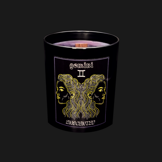 A black candle with a gold and purple label featuring the Gemini zodiac sign.
