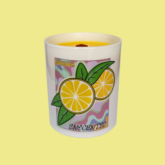 A white candle with a floral and lemon design, labeled 'Lemon Enchanted', against a yellow background