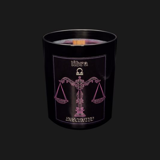 A black scented candle with a purple label featuring the Libra zodiac sign symbol in pink. The candle is named 'LIBRA' and the label includes the phrase 'EMPOWERED'.