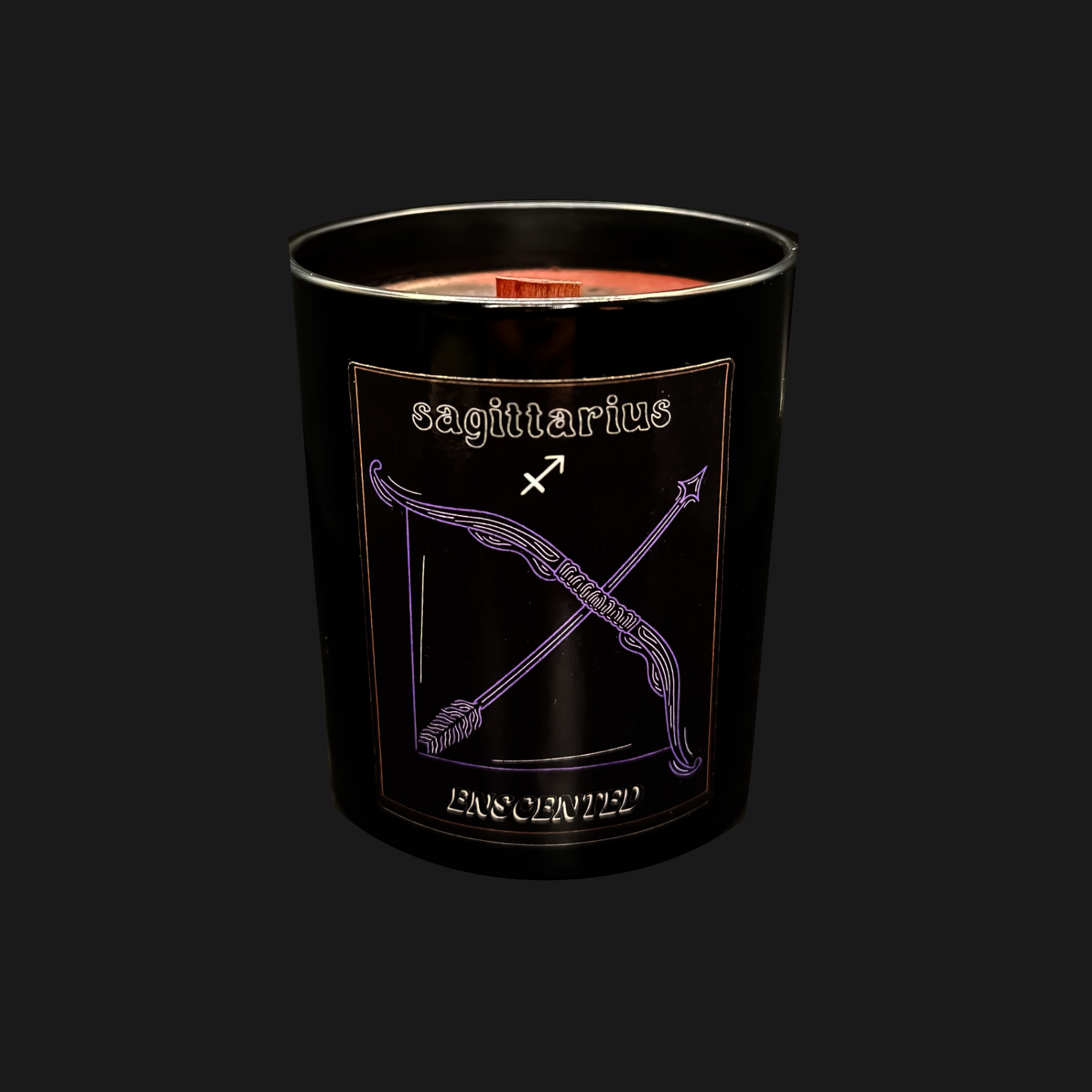 A black soy wax candle with a red candle wick, featuring a purple label with the Sagittarius zodiac sign.